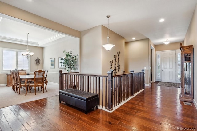 hall featuring dark wood-style floors, a tray ceiling, a notable chandelier, recessed lighting, and baseboards