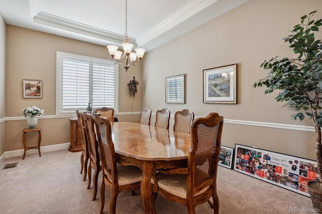 carpeted dining space featuring a raised ceiling, ornamental molding, and an inviting chandelier