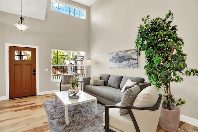 living area featuring light wood finished floors, baseboards, and a high ceiling