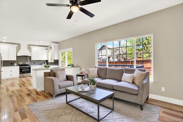 living area with light wood-style flooring, a ceiling fan, baseboards, and recessed lighting