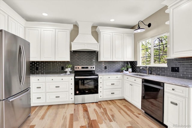 kitchen with stainless steel appliances, custom range hood, a sink, decorative backsplash, and white cabinetry