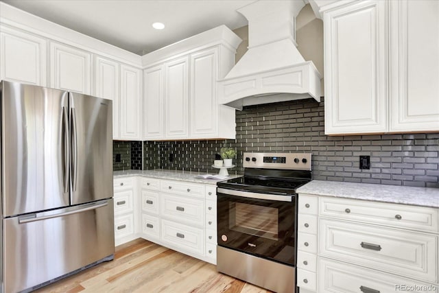kitchen with appliances with stainless steel finishes, premium range hood, backsplash, and white cabinetry