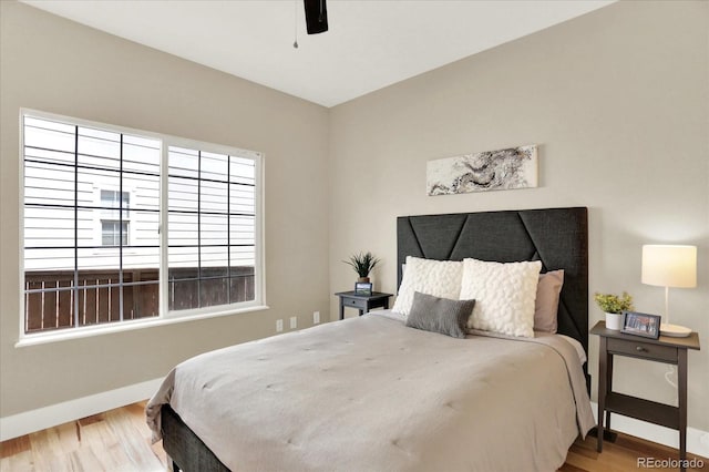 bedroom featuring baseboards, wood finished floors, and a ceiling fan