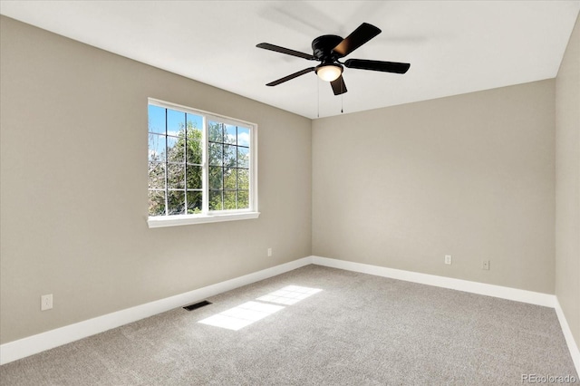 carpeted spare room featuring baseboards and ceiling fan