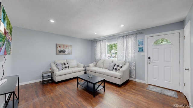 living area with a textured ceiling, recessed lighting, dark wood finished floors, and baseboards