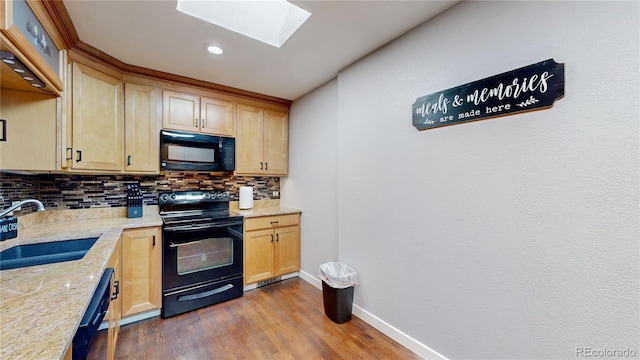 kitchen with light stone counters, wood finished floors, a sink, backsplash, and black appliances