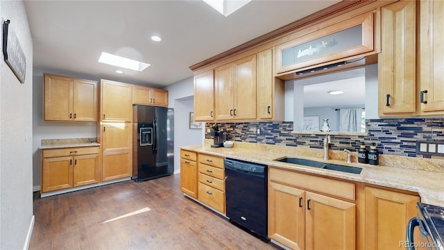 kitchen featuring dark wood-style floors, a skylight, backsplash, a sink, and black appliances