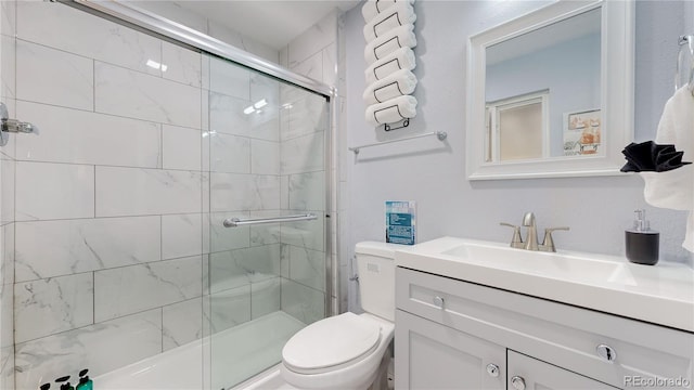 full bathroom with toilet, tiled shower, and vanity