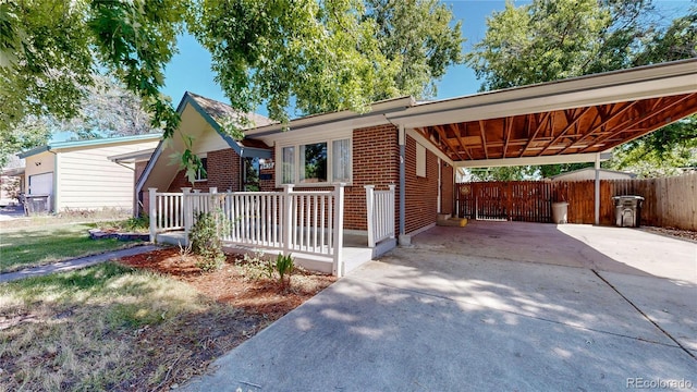 ranch-style home with an attached carport, brick siding, driveway, and fence