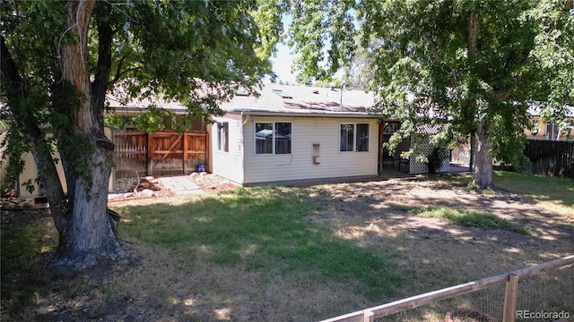 rear view of house featuring a yard and a fenced backyard