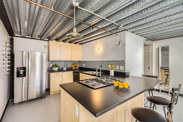 kitchen with backsplash, sink, stainless steel fridge, decorative light fixtures, and electric stovetop