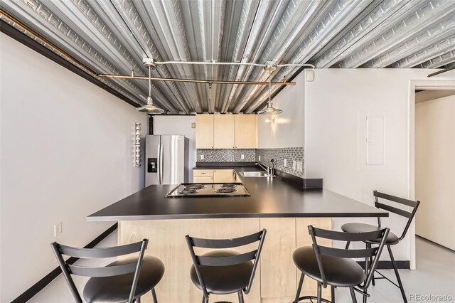 kitchen with sink, tasteful backsplash, kitchen peninsula, a kitchen bar, and appliances with stainless steel finishes