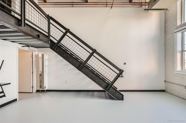 stairway featuring a high ceiling and concrete floors