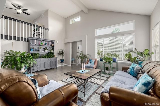 living room with light hardwood / wood-style flooring, beamed ceiling, a high ceiling, and ceiling fan