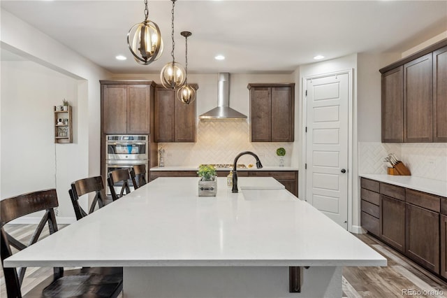 6616 Amur Ln, Castle Rock, CO 80108 - kitchen with wall chimney range hood, double oven, a breakfast bar, a sink, and recessed lighting