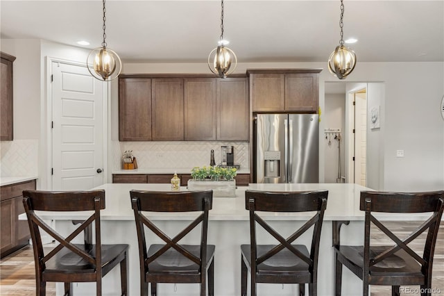 6616 Amur Ln, Castle Rock, CO 80108 - kitchen featuring stainless steel refrigerator with ice dispenser, light countertops, tasteful backsplash, a kitchen island with sink, and recessed lighting