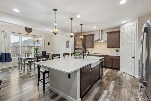 6616 Amur Ln, Castle Rock, CO 80108 - kitchen with wall chimney range hood, stainless steel appliances, a breakfast bar, dark wood-style flooring, and recessed lighting