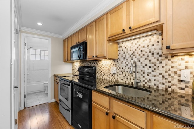 kitchen featuring sink, tasteful backsplash, dark stone countertops, and black appliances