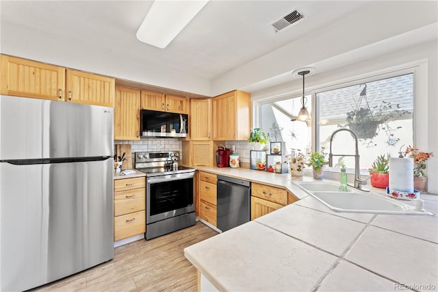 kitchen featuring light wood-type flooring, backsplash, sink, appliances with stainless steel finishes, and light brown cabinets