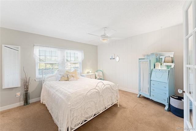 bedroom with a textured ceiling, ceiling fan, wood walls, and light carpet