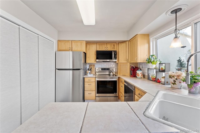 kitchen featuring backsplash, appliances with stainless steel finishes, sink, light brown cabinets, and pendant lighting