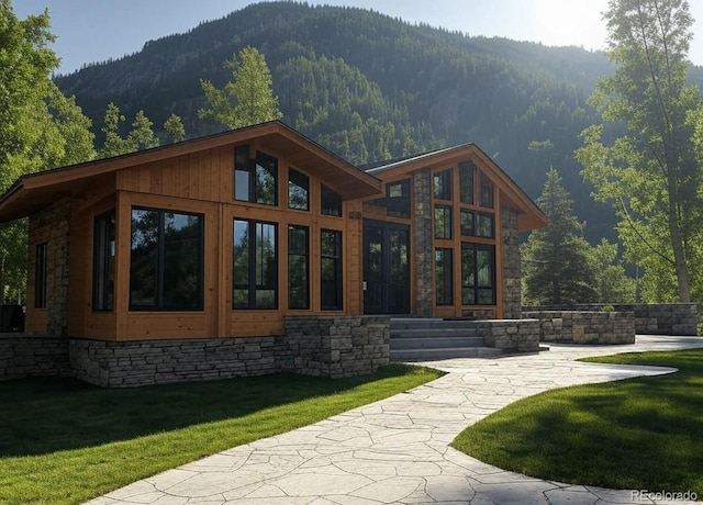 back of house with a mountain view and a lawn