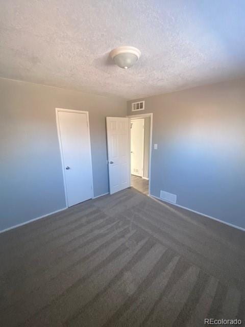 unfurnished bedroom with dark carpet and a textured ceiling