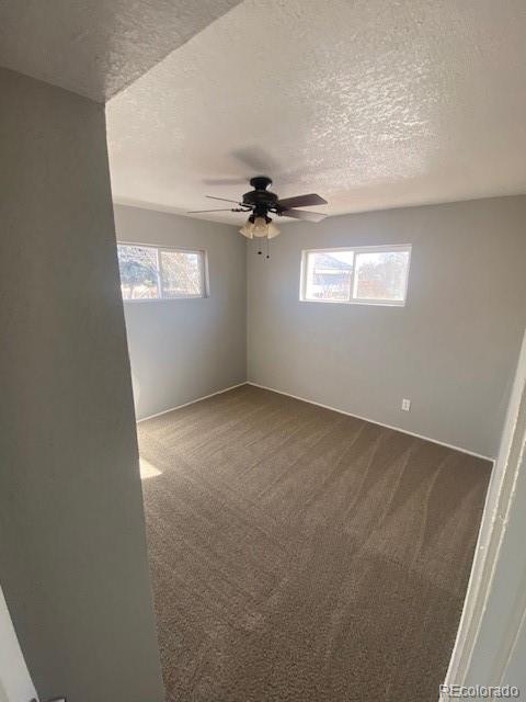 empty room with ceiling fan, carpet, and a textured ceiling