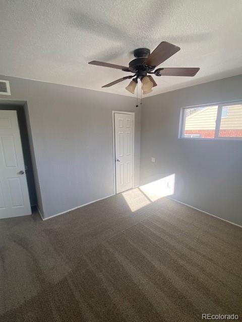 carpeted spare room with a textured ceiling and ceiling fan