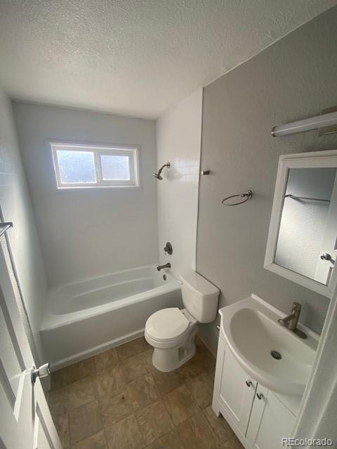 full bathroom with vanity, a textured ceiling, bathing tub / shower combination, and toilet