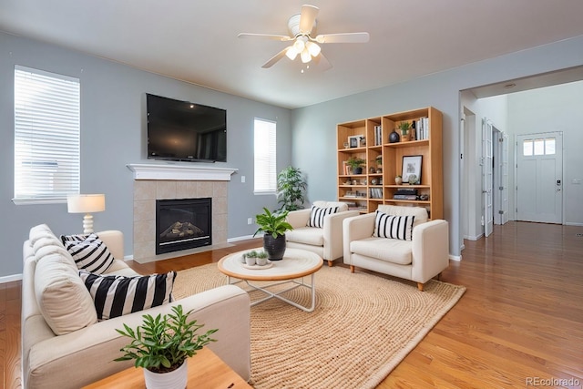 living room featuring ceiling fan, wood-type flooring, and a tile fireplace