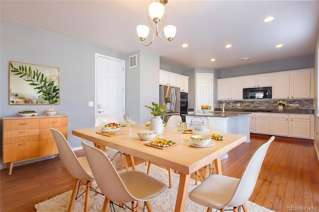 dining area with a chandelier, sink, and light hardwood / wood-style flooring