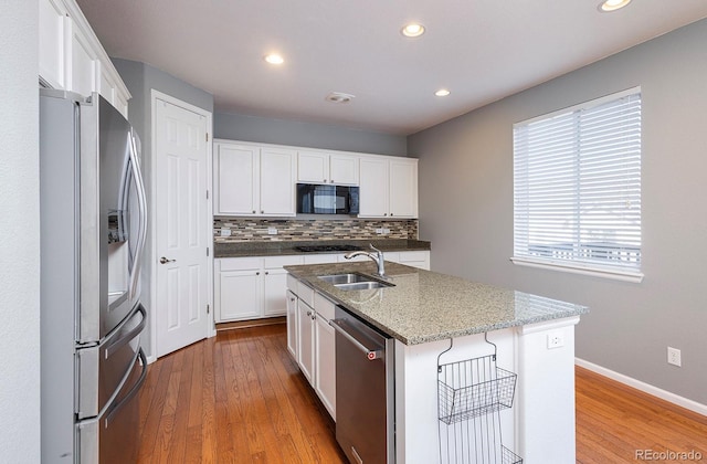 kitchen with hardwood / wood-style flooring, white cabinetry, a kitchen island with sink, and appliances with stainless steel finishes