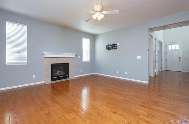 unfurnished living room featuring ceiling fan, a fireplace, and light hardwood / wood-style flooring