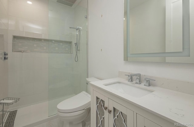 bathroom with vanity, toilet, and tiled shower