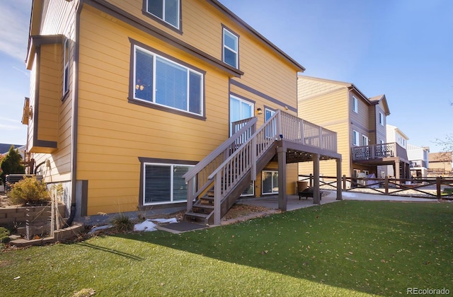 rear view of property featuring a lawn, a patio area, and a wooden deck