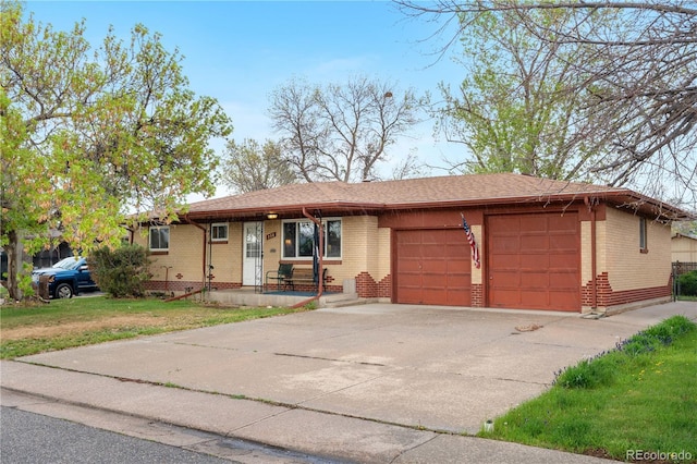 ranch-style home featuring brick siding, a garage, driveway, and a front yard