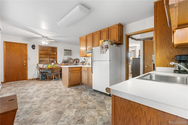 kitchen with freestanding refrigerator, a sink, light countertops, ceiling fan, and brown cabinetry