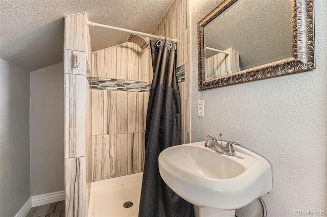 4037 S Odessa Cir, Aurora, CO 80013 - bathroom featuring a sink, a textured ceiling, a textured wall, and a stall shower