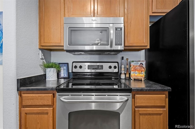4451 S Ammons St Unit 4-203, Littleton, CO 80123 - kitchen with appliances with stainless steel finishes, dark countertops, and a textured wall