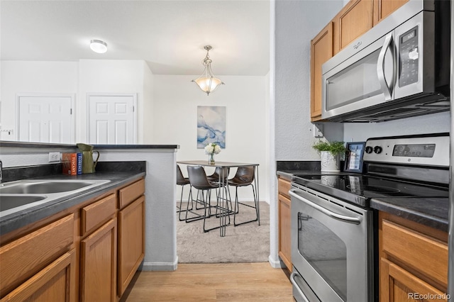 4451 S Ammons St Unit 4-203, Littleton, CO 80123 - kitchen with stainless steel appliances, dark countertops, light wood-style floors, and brown cabinets