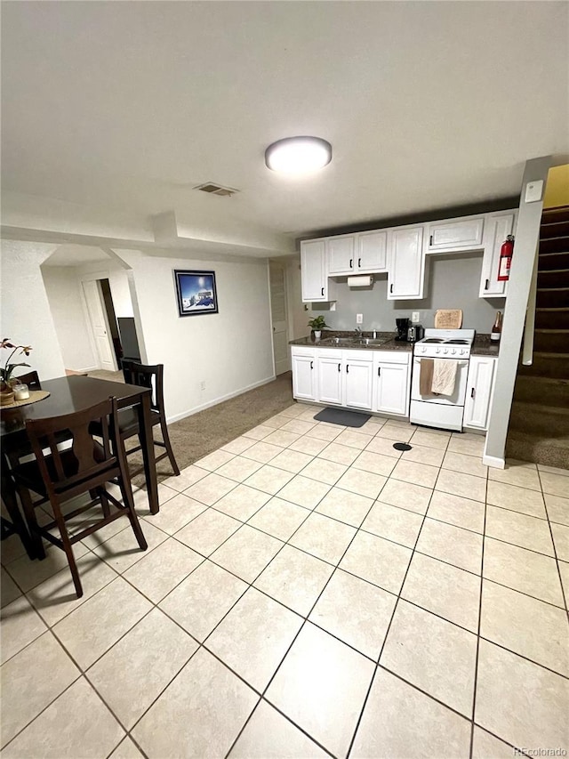 kitchen featuring white range with electric cooktop, dark countertops, visible vents, white cabinetry, and light tile patterned flooring