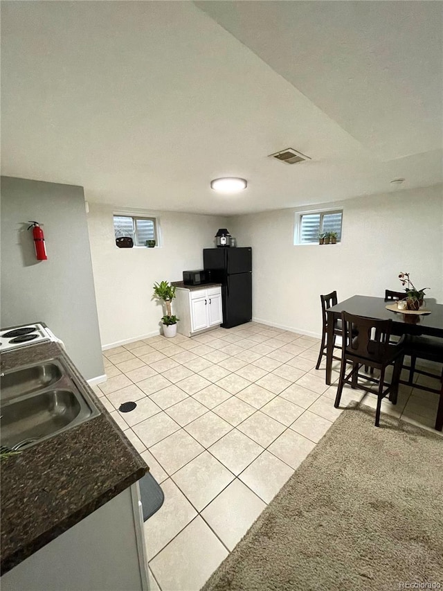 kitchen with light tile patterned flooring, a sink, white cabinetry, baseboards, and freestanding refrigerator