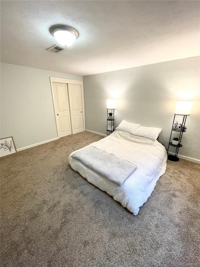 bedroom with carpet flooring, visible vents, baseboards, and a textured ceiling