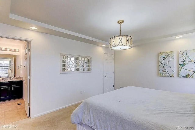 bedroom featuring ensuite bathroom and light carpet