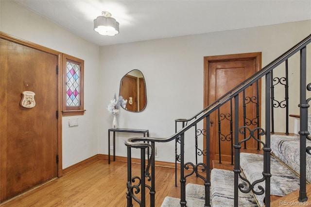 foyer featuring light wood-style floors, baseboards, and stairway