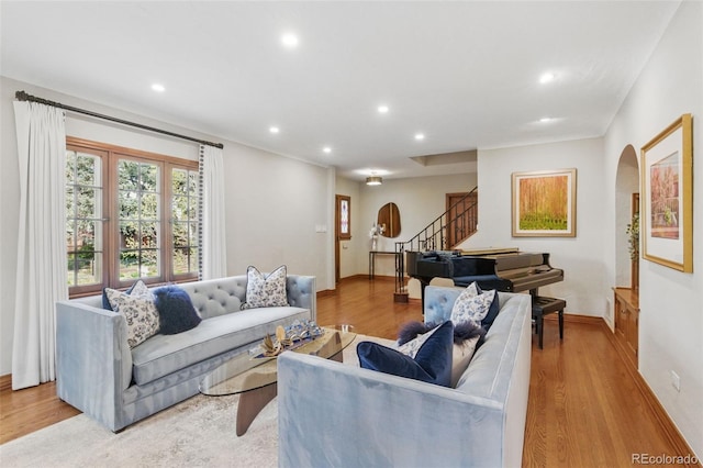 living area featuring recessed lighting, arched walkways, wood finished floors, and stairway