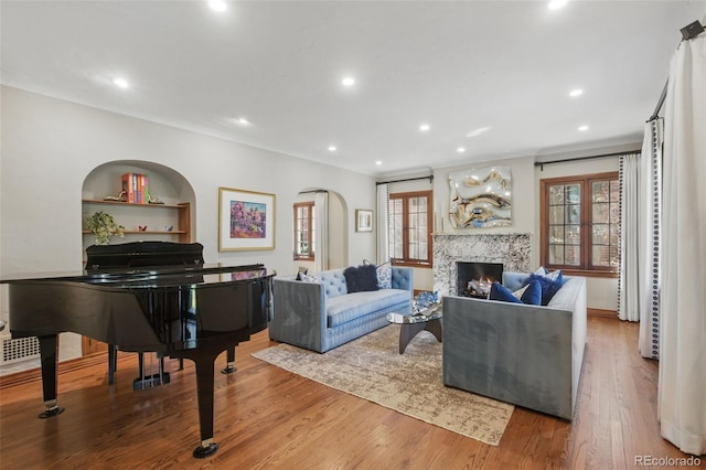 living room featuring recessed lighting, arched walkways, wood finished floors, and a fireplace