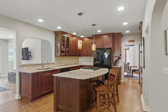 kitchen with arched walkways, decorative backsplash, a sink, and a center island