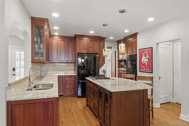 kitchen featuring a sink, light stone counters, multiple ovens, and freestanding refrigerator